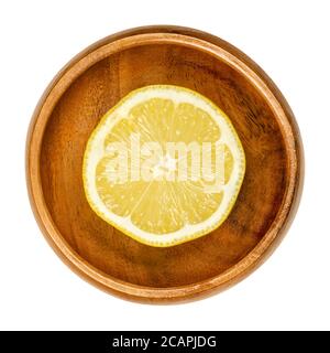 Lemon half in wooden bowl. Freshly cut ripe yellow edible citrus fruit. Citrus limon. Lemon juice is used for culinary purposes and for cleaning. Stock Photo