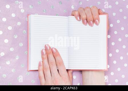 Open blank notebook in female hands. Place for text. Shiny paper on background Stock Photo
