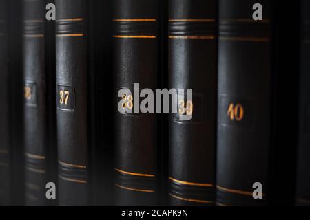 Collection of a multi-volume old encyclopedia in a dark, worn cover with yellowish numbers. Books with knowledge and information. Learning. Stock Photo