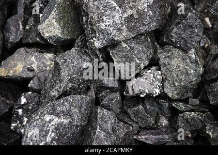 Wet natural black fragments of stones with interspersed marbles for backgrounds, top view. Large broken pieces of stone. Heap of black wet stones Stock Photo