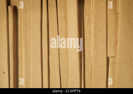 Plastered and painted wall textured background. Molding on textured wall, exterior wall of exposed building illuminated by sunlight. Stock Photo