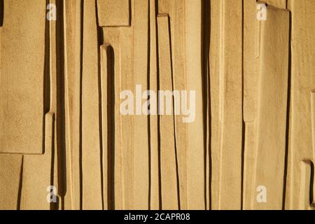 Plastered and painted wall textured background. Molding on textured wall, exterior wall of exposed building illuminated by sunlight. Stock Photo