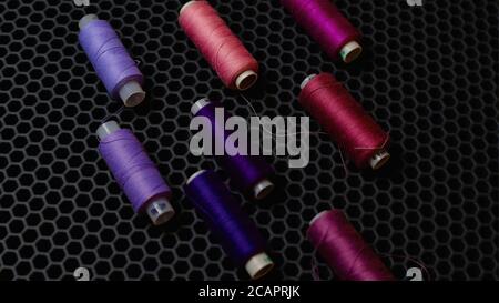 Multi-colored sewing threads diagonally against a dark background from above Stock Photo