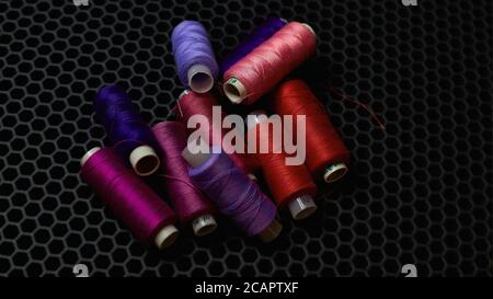 Multi-colored sewing threads on a dark background close-up from above Stock Photo
