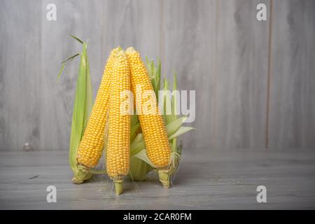 Group of raw corn cob with husks on a wooden background Stock Photo