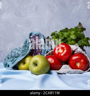 Apples, tomatoes, fresh herbs and red cabbage in zero waste bags, selective focus Stock Photo