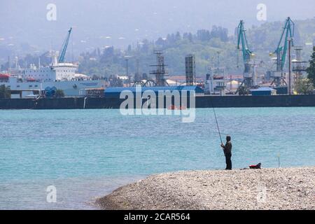 Fisherman with fishing rod near cargo port in Batumi, Georgia Stock Photo