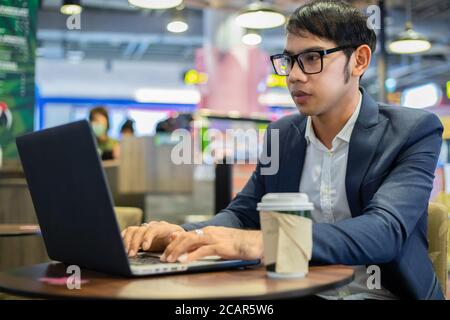 Asian businessmen are talking on the phone and drinking coffee while working Stock Photo