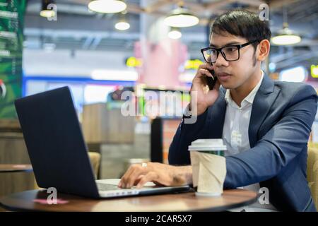 Asian businessmen are talking on the phone and drinking coffee while working Stock Photo