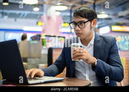 Asian businessmen are talking on the phone and drinking coffee while working Stock Photo