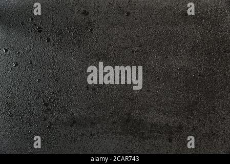 The rough surface of black slate stone, covered with small drops of water. Abstract background Stock Photo