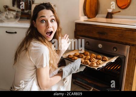 Cheerful young girl taking baked cookies from the oven Stock Photo