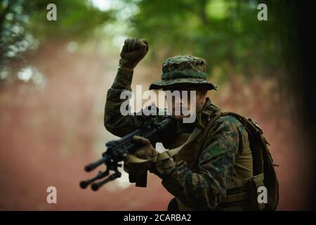 modern warfare soldier officer is  showing tactical hand signals to silently give orders and alers for squad team forest enviroment Stock Photo