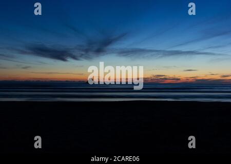 Late evening sunset views of the Pacific Ocean with rock formations and deep rich in the sky. Stock Photo