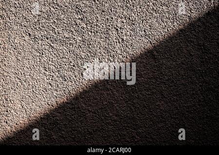 Bronze textured background split diagonally into brightly lit and shade areas. Stock Photo