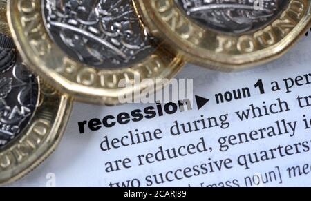 BRITISH ONE POUND COINS WITH DICTIONARY DEFINITION OF WORD RECESSION RE THE ECONOMY CORONAVIRUS COVID-19 PANDEMIC GLOBAL ETC UK Stock Photo