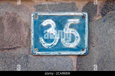 Thirty-five, number 35, blue digit plate on a stone gray background. Stock Photo