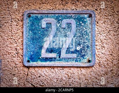 22, number twenty-two, old blue metal numeral plate on a wall. Stock Photo