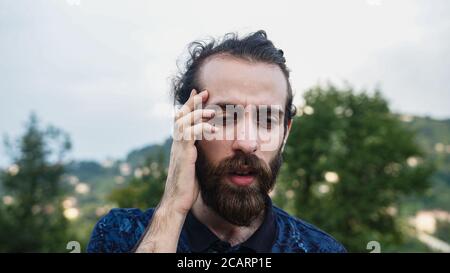 Handsome hipster man with long hair and beard suffering a headache looks sad Stock Photo