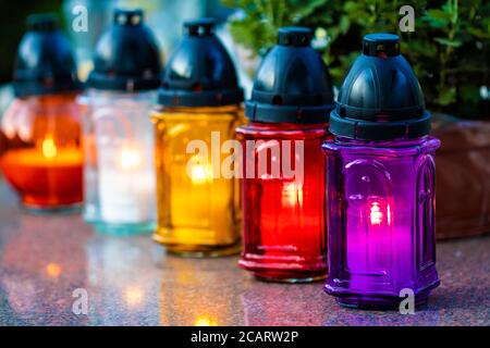 Row of colourfull burning grave candles on a grave during All Souls' Day Stock Photo
