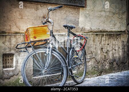 old bike with wooden case against a wall in florence, Italy Stock Photo