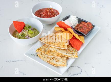 Plate of Mexican tortilla chips with herbs accompanied by sauces Stock Photo