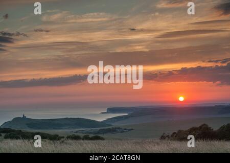 Eastbourne, East Sussex, UK. 8th Aug, 2020. Amazing colours & interesting clouds at sunset. A glorious end to a scorching day on the South coast. The Belle Tout lighthouse left of centre, overlooking Birling Gap toward Seaford & Newhaven. Taken from Beachy Head area. Credit: David Burr/Alamy Live News Stock Photo