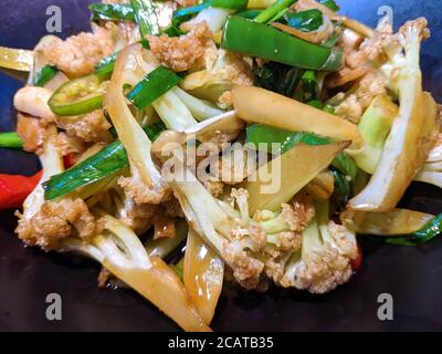 scrambled white cauliflower with green pepper in the plate under bright light Stock Photo