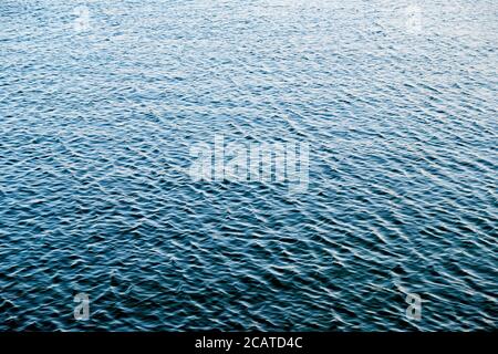 Lake surface on a calm day with ripples on blue water. Stock Photo