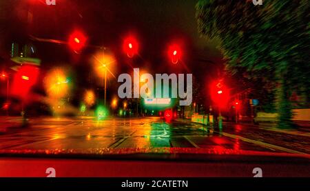 View through a front window of a car at the night stop at a colorful reflecting traffic light scenery in a town. Stock Photo