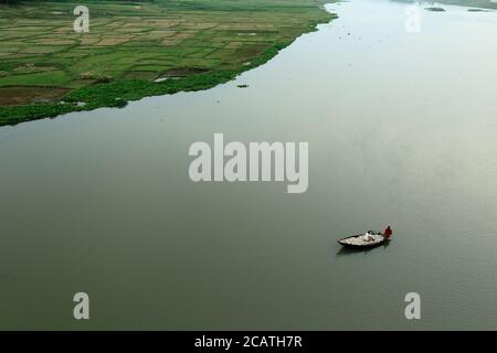 Top view of the river, towing boat pulls the barge with wooden materials in the summer evening. Aerial view of the landscape from the air. Stock Photo
