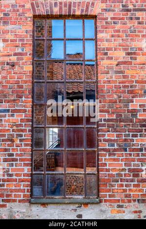 Old window on an industrial building with a brick wall Stock Photo