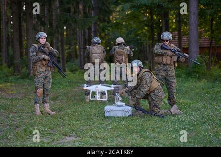 Modern Warfare Soldiers Squad are Using Drone for Scouting and Surveillance During Military Operation in the Forest. Stock Photo