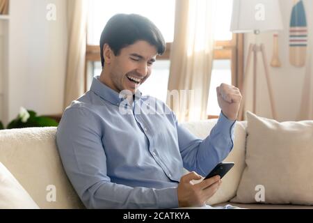 Happy young handsome man celebrating online lottery win. Stock Photo