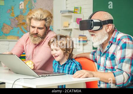 Three generations of men having fun together. GrandFather, father and son playing computer games at home. Parenting childhood values weekend. Stock Photo