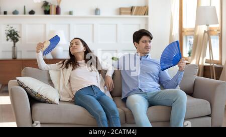 Stressed tired young family couple fanning fresh air. Stock Photo