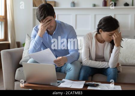 Unhappy young family couple feeling stressed about banking debt. Stock Photo