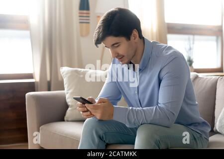 Pleased young handsome happy guy using smartphone. Stock Photo