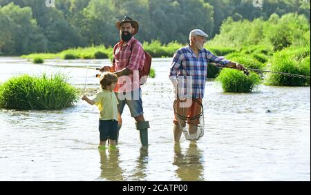 Man in different ages. Fishing. Grandpa and grandson are fly fishing on river. Man teaching kids how to fish in river. Stock Photo