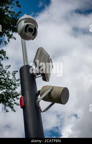 CCTV dome security camera and LED floodlight on a pole in sky Stock Photo