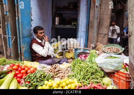 Agra / India - February 22, 2020: indian man at colorful street stall selling vegetables Stock Photo