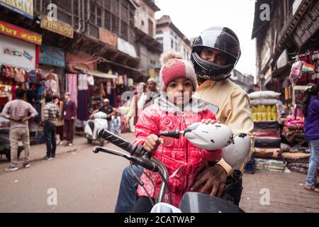 Agra / India - February 22, 2020: portrait of father and daughter on motorcycle in downtown Agra street Stock Photo
