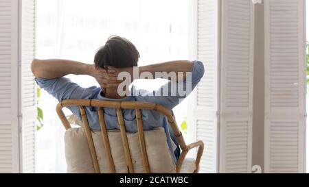 Rear view dreamy calm young man relaxing on cozy chair Stock Photo