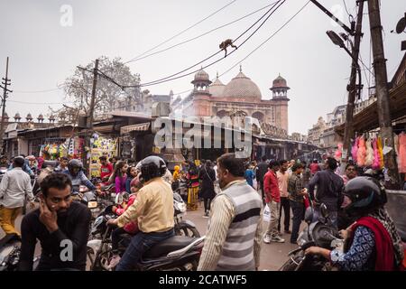 Agra / India - February 22, 2020: people walking down street of historical center of Agra with Jama Masjid in the background and monkeys walking on wire Stock Photo