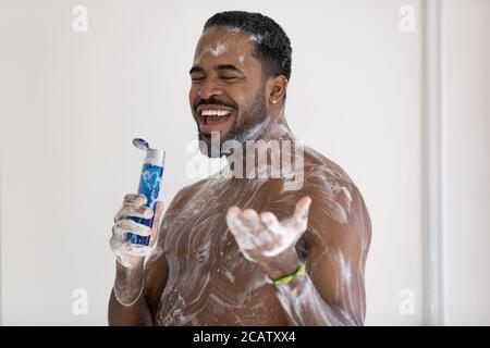 Smiling cheerful African American young man singing in shower Stock Photo