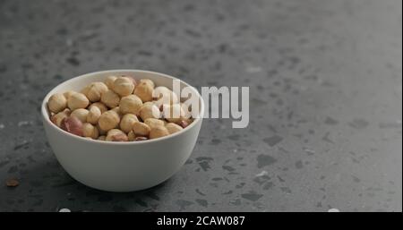 roasted hazelnuts in white bowl on terrazzo countertop Stock Photo