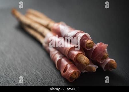 grissini breadsticks with prosciutto on slate background Stock Photo