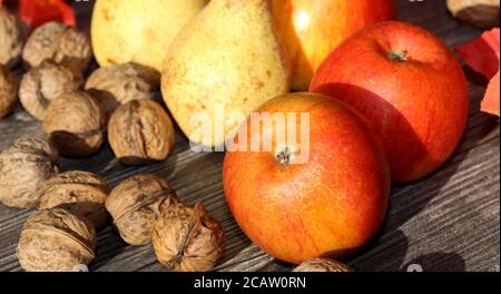 Apples, pears and wal nuts on a rustic wooden table as autumn motif Stock Photo
