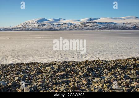 Snowy landscape in spring time with mountains in background, frozen lake Torneträsk,  Kiruna county, Swedish Lapland, Sweden Stock Photo