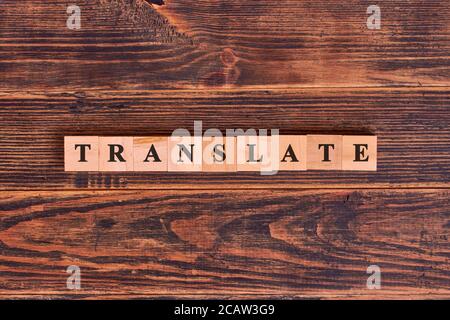 Translate word lettering made of wooden cubes on dark rustic wooden background. Multilingual online translator, business and technology concept Stock Photo